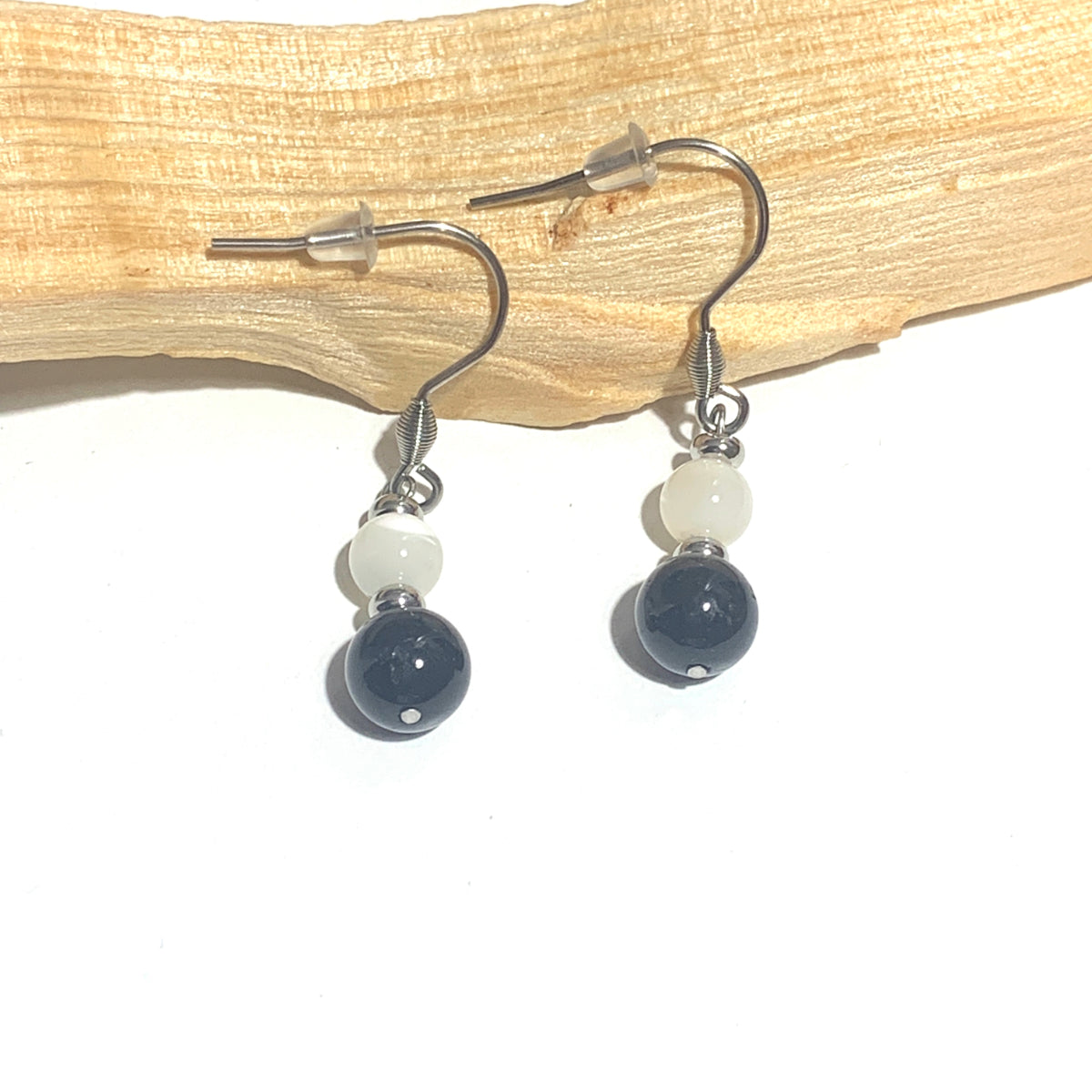 Boucles d'oreilles pendantes en acier inoxydable avec tourmaline noire et nacre. Un bijou alliant protection et douceur pour un style unique et raffiné